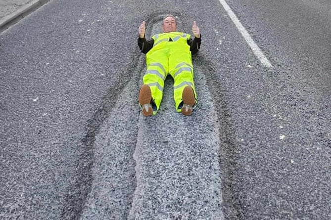 David Newcombe's lie-down protest to highlight the huge pothole on Tavistock's Plymouth Road.