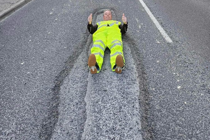 David Newcombe shows off the now repaired 15-ft long pothole on Plymouth Road.