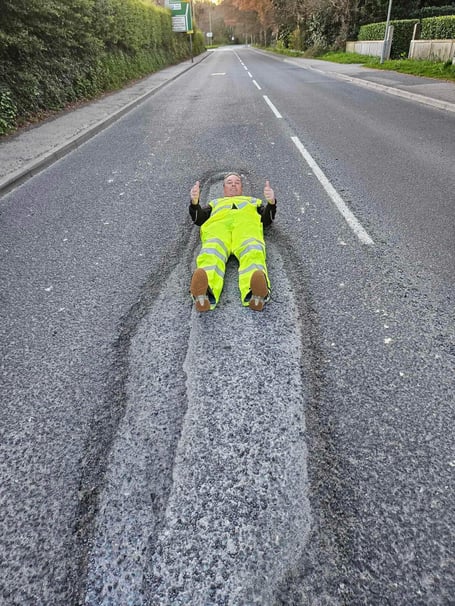 David Newcombe shows off the now repaired 15-ft long pothole on Plymouth Road.