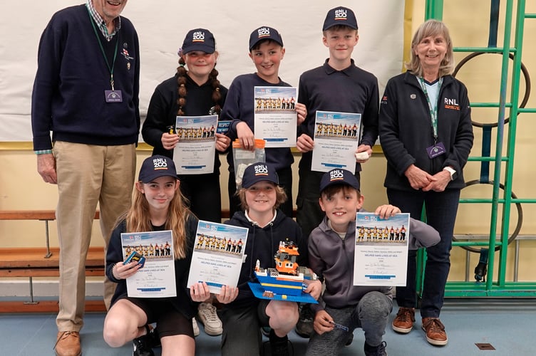Chair of Tavistock Branch of the RNLI, Daniel Leonard-Williams, and treasurer Heather Webster with the six pupils and their certificates, caps and Lego lifeboat.