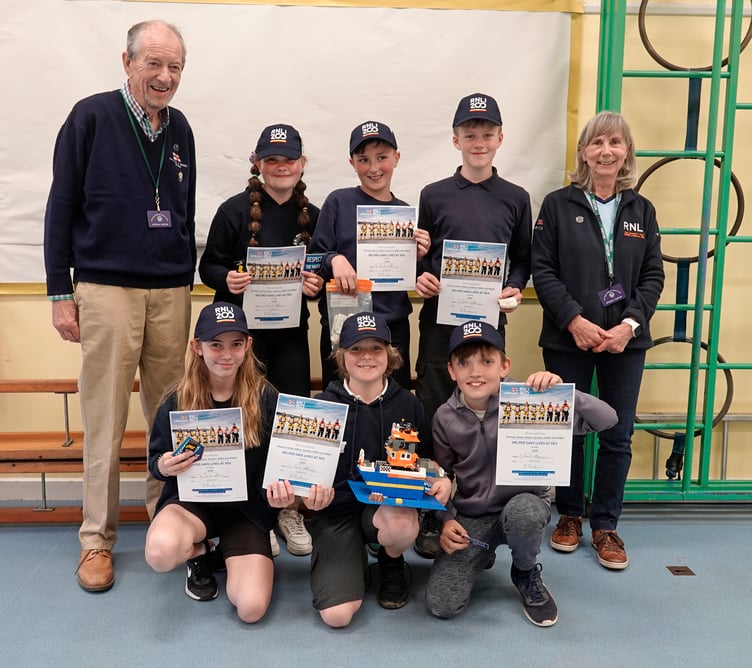 Chair of Tavistock Branch of the RNLI, Daniel Leonard-Williams, and treasurer Heather Webster with the six pupils and their certificates, caps and Lego lifeboat.