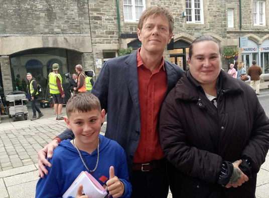 Star of Beyond Paradise Kris Marshall makes it a day to remember for mum Emma Monk and her son George by breaking off filming in Tavistock to sign his book an pose for a photo.