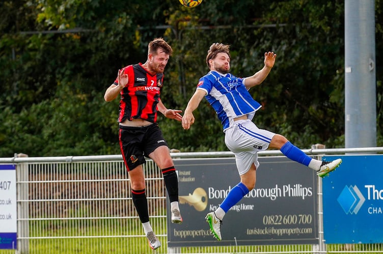 Faces of concentration as two players go up for a header at Tavistock AFC
