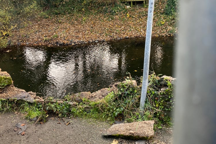 The Market Road river wall in Tavistock destroyed by a traffic collision on Monday and fenced off for safety.