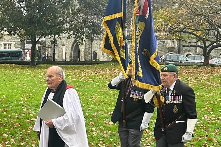 Two veterans with military colours flying honour Lt Col Peter Cameron.
