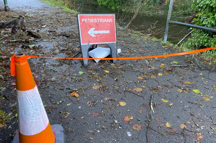 Storm damage on the River Tavy at Tavistock. A fallen tree has damaged a wall and Tarmac path alongside the Abbey Car Park. A section of the path is closed.