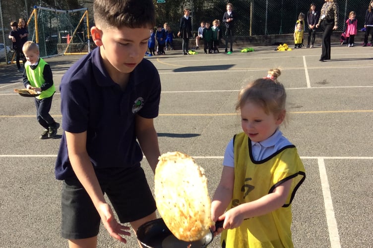 Some expert tuition in pancake flipping before the Shrove Tuesday race at Whitchurch School.