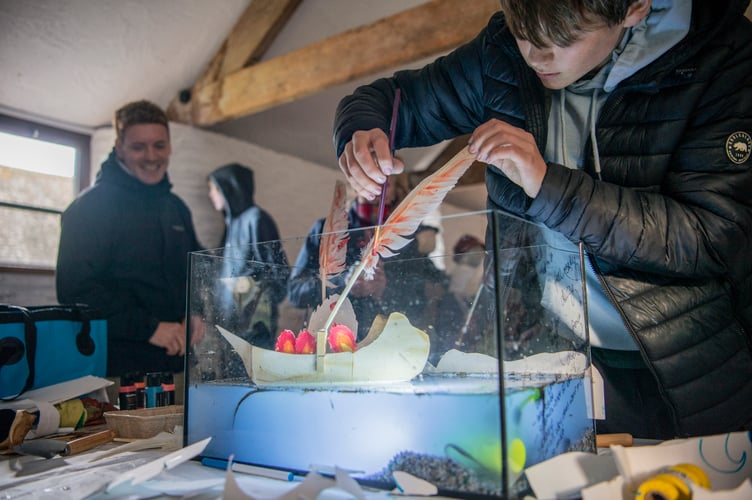 A young person from Tavistock Youth Cafe works with his group to create a mini-seascape called 'Hell Burners' at Buckland Abbey.