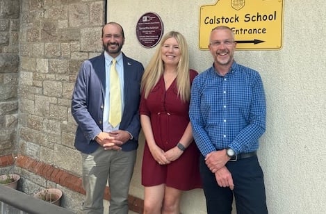 Angelo Spencer- Smith (Innovate UK), Sam Jackman (Boost), Ben Towe (Headteacher, Calstock Primary) with purple plaque outside the school entrance 