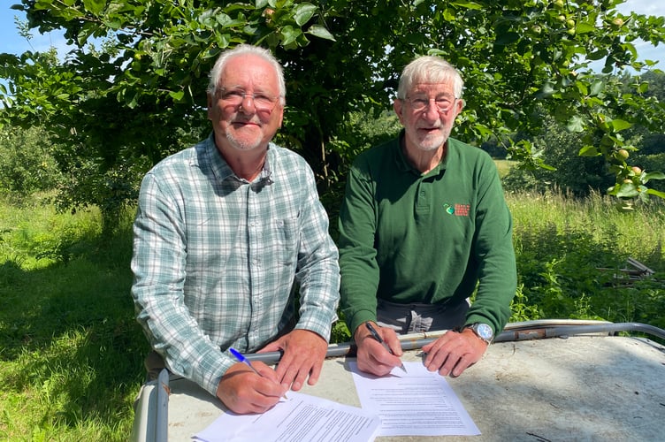 Bere Ferrers Orchard has now been taken on by the Tavy and Tamar Apple Group as a community asset after a ceremonial signing by Bere Ferrers Parish Council chair (L) Richard Leithall and Graham Reed of the group.
