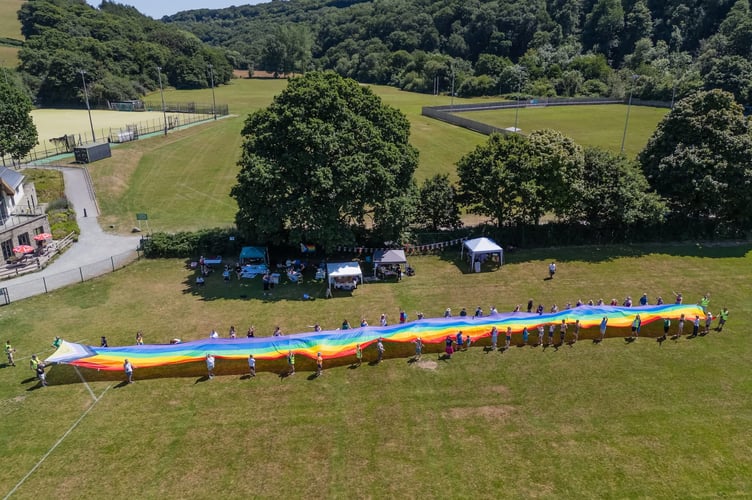 A drone image by Rob Greaves of people holding the giant rainbow flag at Okehampton Pride.