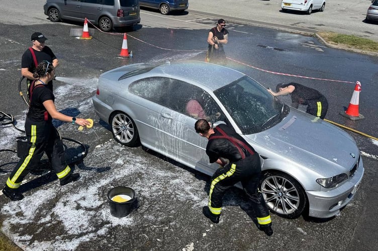 The fire fighters hard at work cleaning a car.