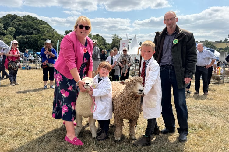 Young sheep handler champion was Jack Darke (7), third left, from Kingsbridge, and runner-up was his cousin, Freya Uglow (4), from Launceston. Left is judge Ann Willcocks from Ivybridge and right, Colin Braine from Okehampton, who made and presented Jack with a shepherd’s crook. AQ 0974