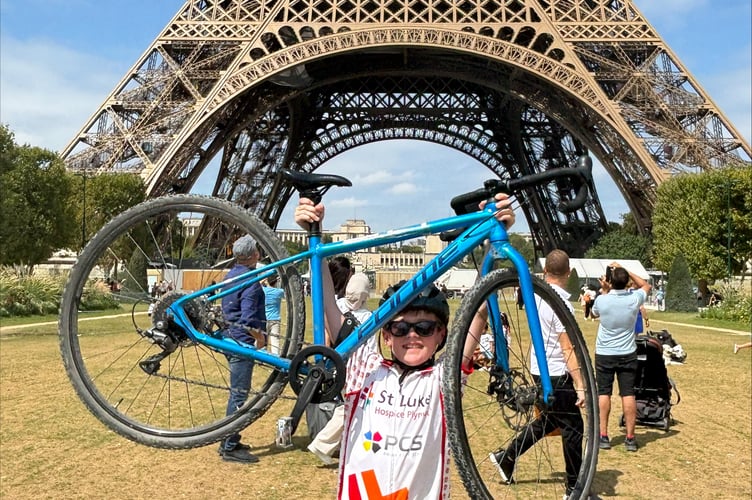 Luke proudly holds his bike aloft in front of the Eiffel Tower.