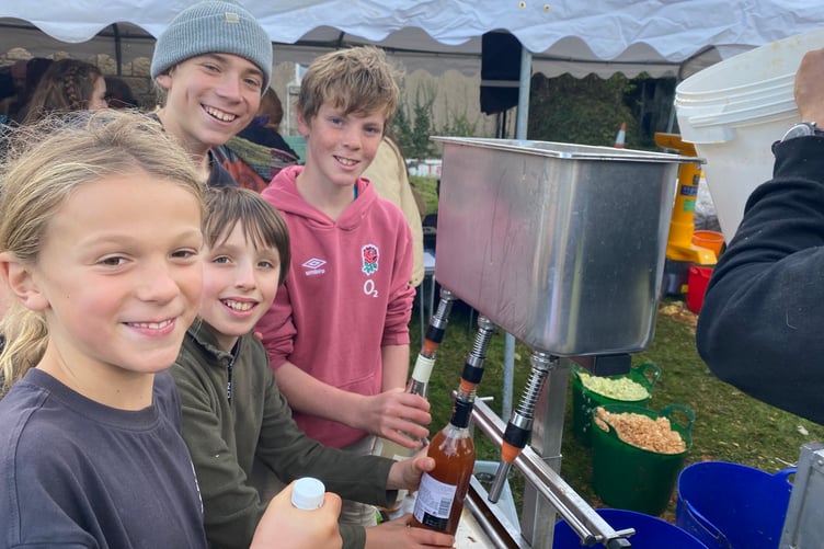 Youngsters bottling freshly pressed apple juice as it is topped up at Bere Applefest in Bere Ferrers.