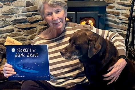 Mary Framptom-Price with her dog Elly with a copy of Secrets of Being Brave by writer Jane Thomas.