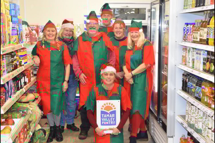 Volunteers Phyl Gates, Chris Clarke, Gavin Short, Malcolm Rowe, Michelle Turner, Lindsey Sharp and Committee Member Karen Bennett (kneeling) get into the Christmas spirit at the Tamar Valley Pantry, Harrowbarrow and Metherell’s new community-run shop. 