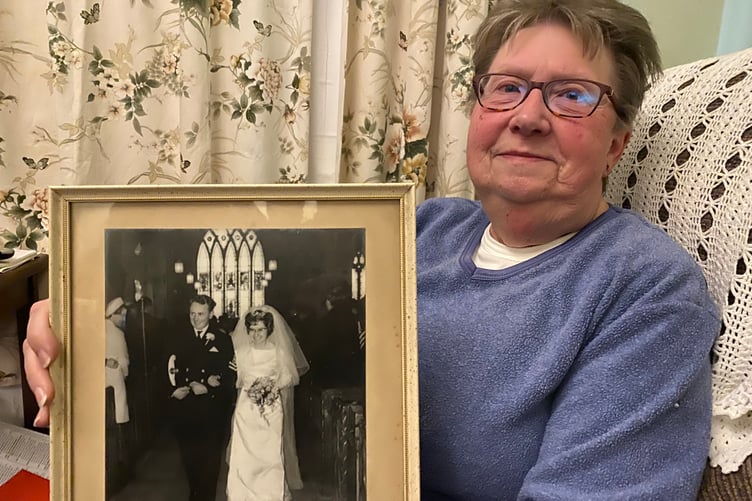 Diana, the widow of the late Robin Pike. She is holding a photo of their wedding in Bere Ferrers Church.