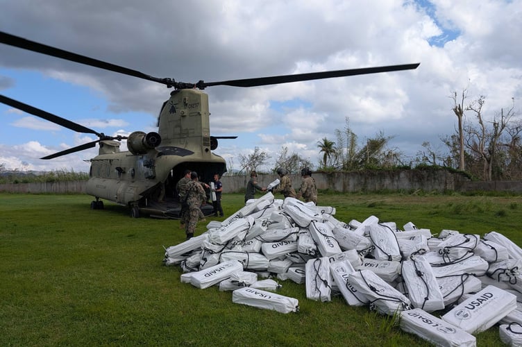 A REACT volunteer worker loading emergency accommodation kits onto a helicopter during the Jamaica hurricane disaster. Picture by Kirsten Edmonds-Bailey.