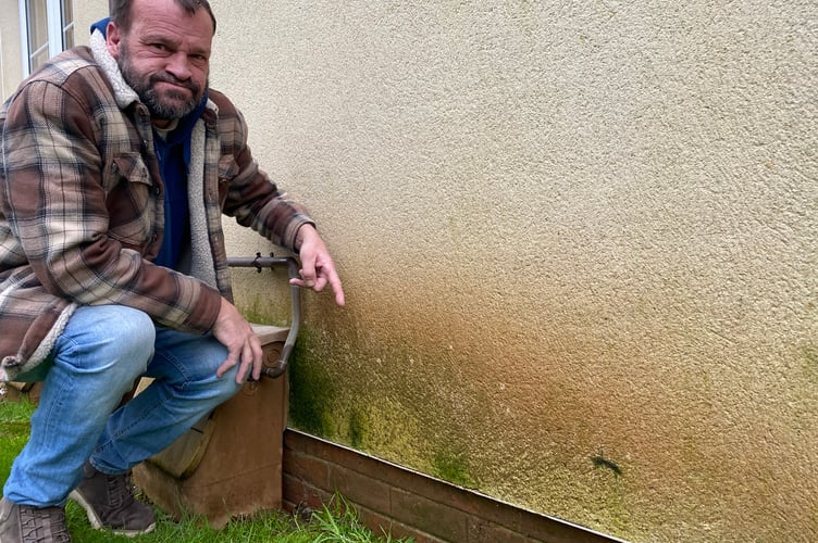 Darren Wonnacott says his damp flat is a health hazard. He is pictured showing the damp spreading from the ground outside.
