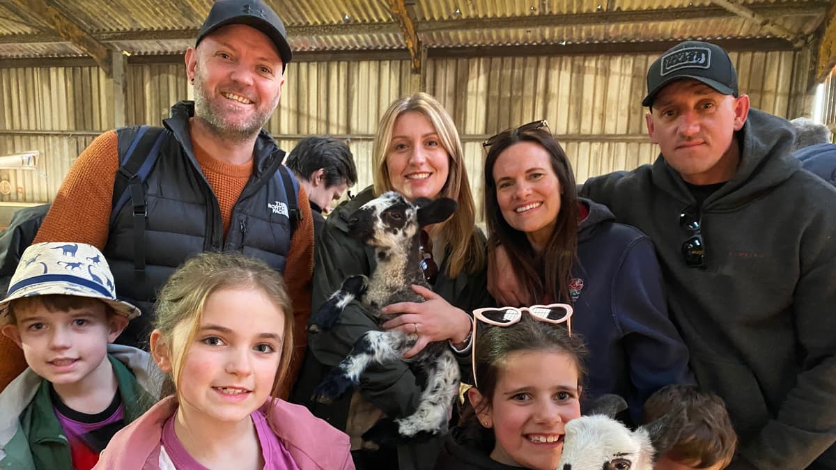 Familien begrüßen Lämmer beim Tag der offenen Tür auf der Meavy Farm