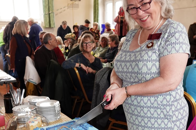 Nicola Gurr (Deputy Lieutenant of Devon)cutting the cakes, made by Glenys Whelan, at the 20-year anniversary of the Bere Ferrers Community Shop in the church hall. Photo by Ann Parsons.