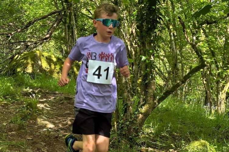 A young runner enduring the heat in the Langstone Fell Race gets some relief in the woodland shade.