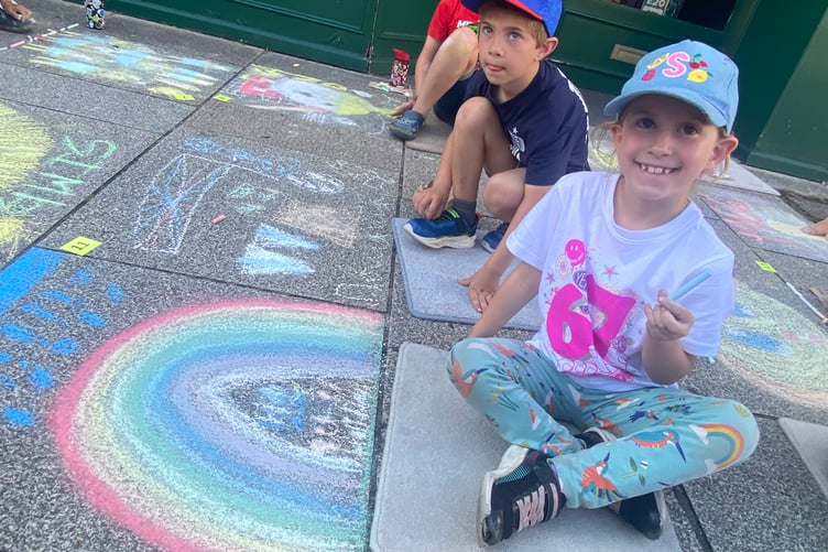 Keen young artists decorate Tavistock high street for the Lions Carnival Week pavement art competition.