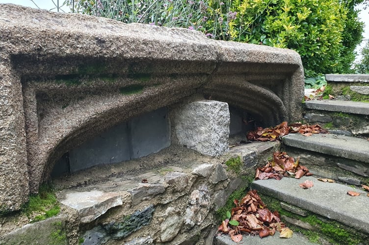 A major piece of granite stonework, possibly an entrance arch top from the former Tavistock Abbey, provides an historic backdrop to a private garden in Tavistock.