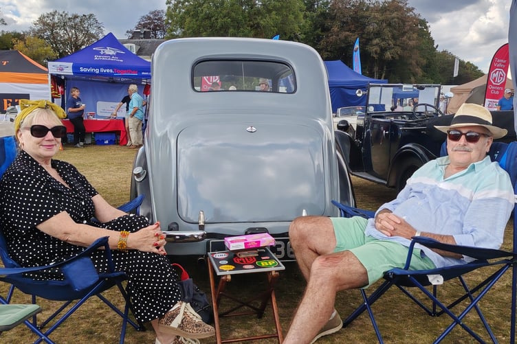 Soaking up the nostalgic atmosphere at the RAF Harrowbeer 1940s Weekend are the proud owners of a classic car on display.