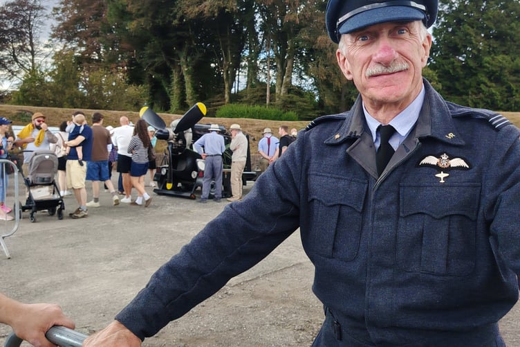 Looking smart in a wartime RAF uniform at RAF Harrowbeer 1940s Weekend while visitors are impressed by a stand-alone aeroplane engine in the background.