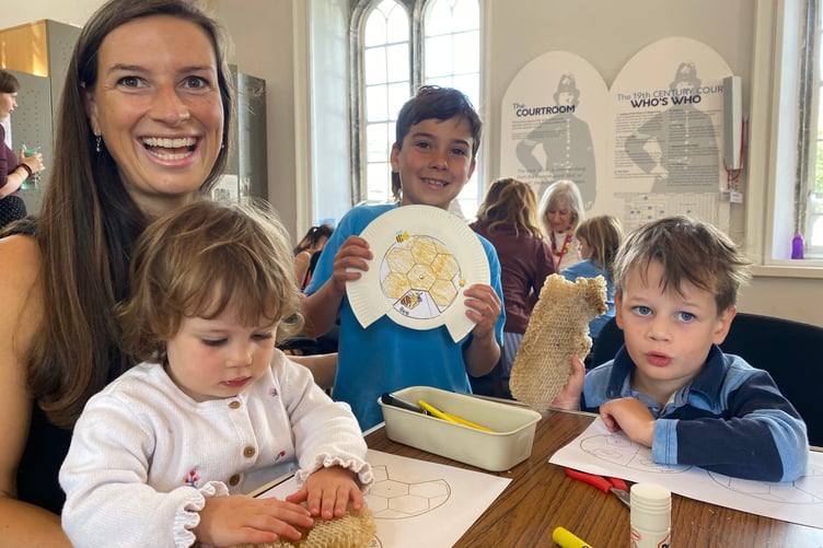 A young family and friend enjoying a summer holiday craft session at Tavistock Guildhall court room.