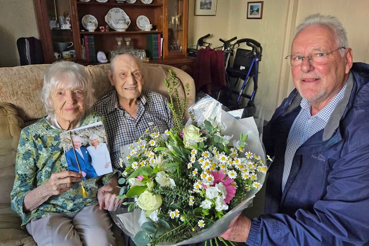 Joan and Ron Haycock are presented with a bouquet of flowers to mark their platinum wedding anniversary by Cllr Richard Leithall, chair of Bere Ferrers Parish Council.